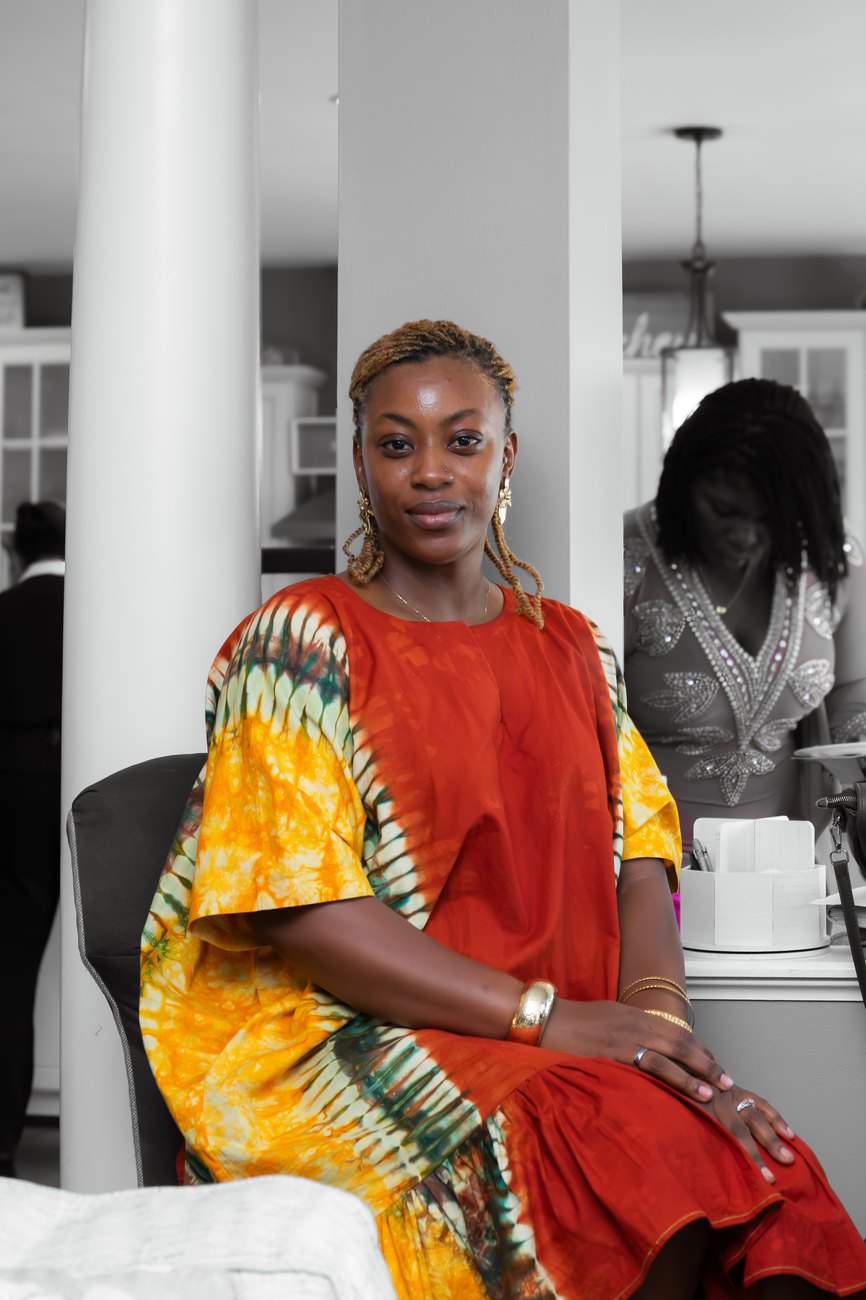 A woman in a red and gold tie-dye gown seated at The MEND Experience